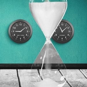 Digital composition of hour glass against clocks with different time zones